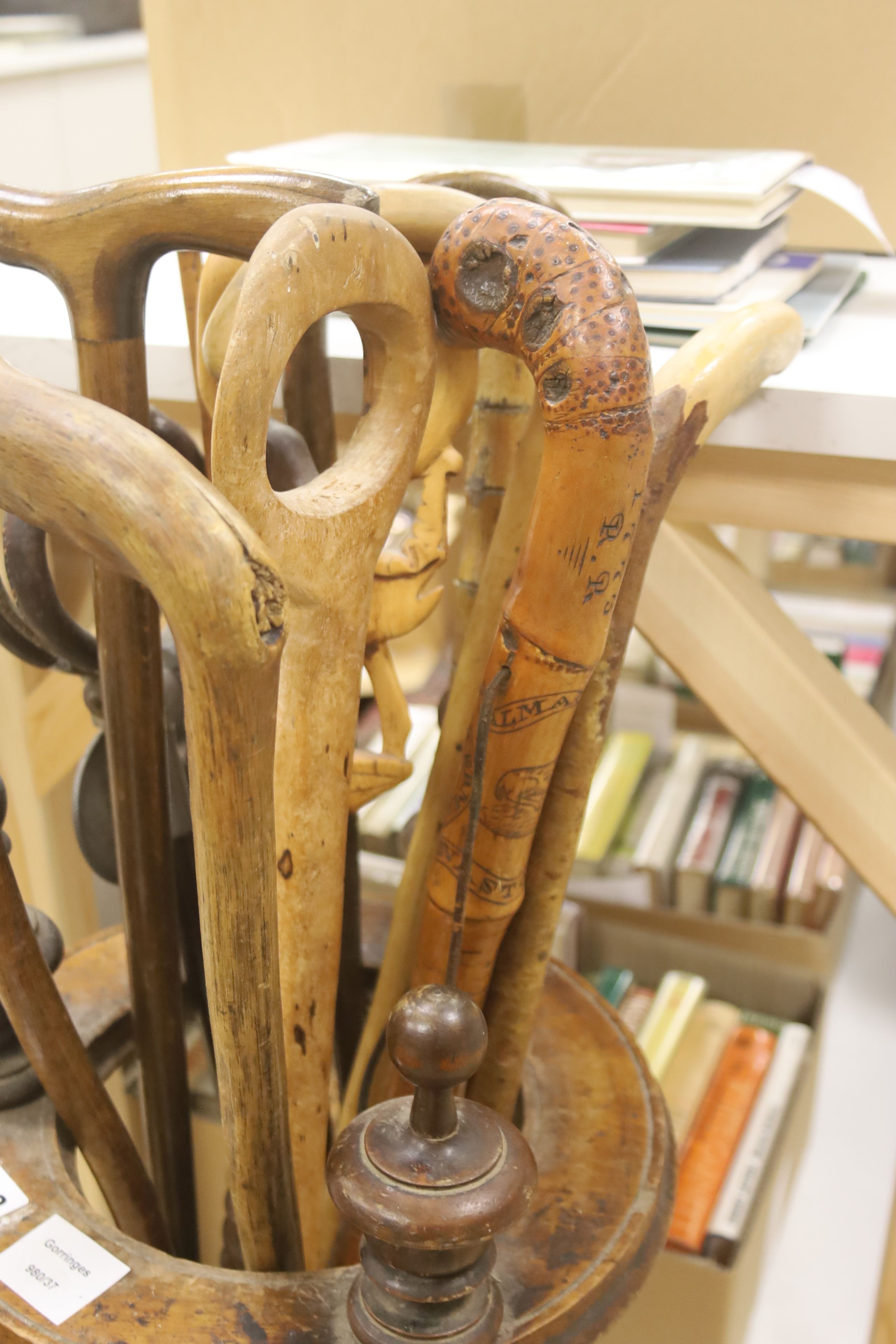 A circular turned beech stick stand, containing various walking sticks and a shooting stick
